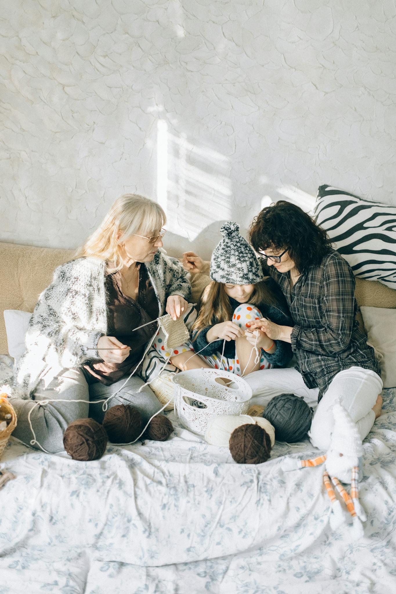 Grandmother teaching granddaughter to crochet, a cozy family moment indoors.