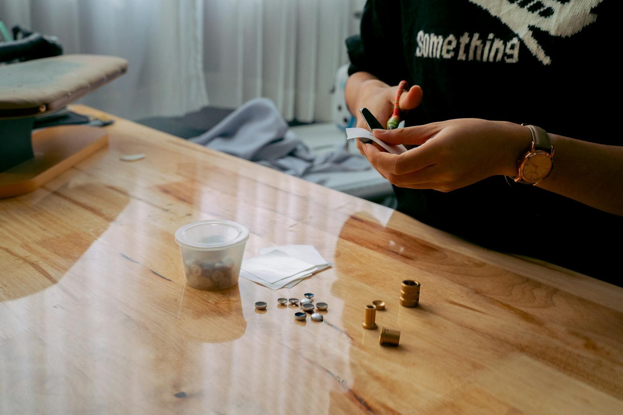 Woman crafting with tools and materials on a wooden table indoors.